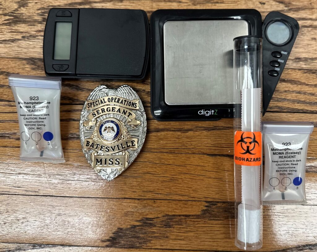 Photo with police badge along with confiscated drug paraphernalia
